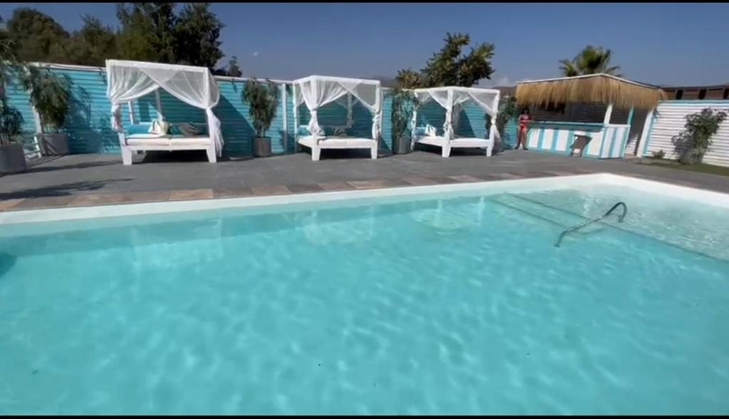 a swimming pool with two white chairs and a swimming pool at Cabañas Boutique Aires del Toro, Curacaví in Curacaví