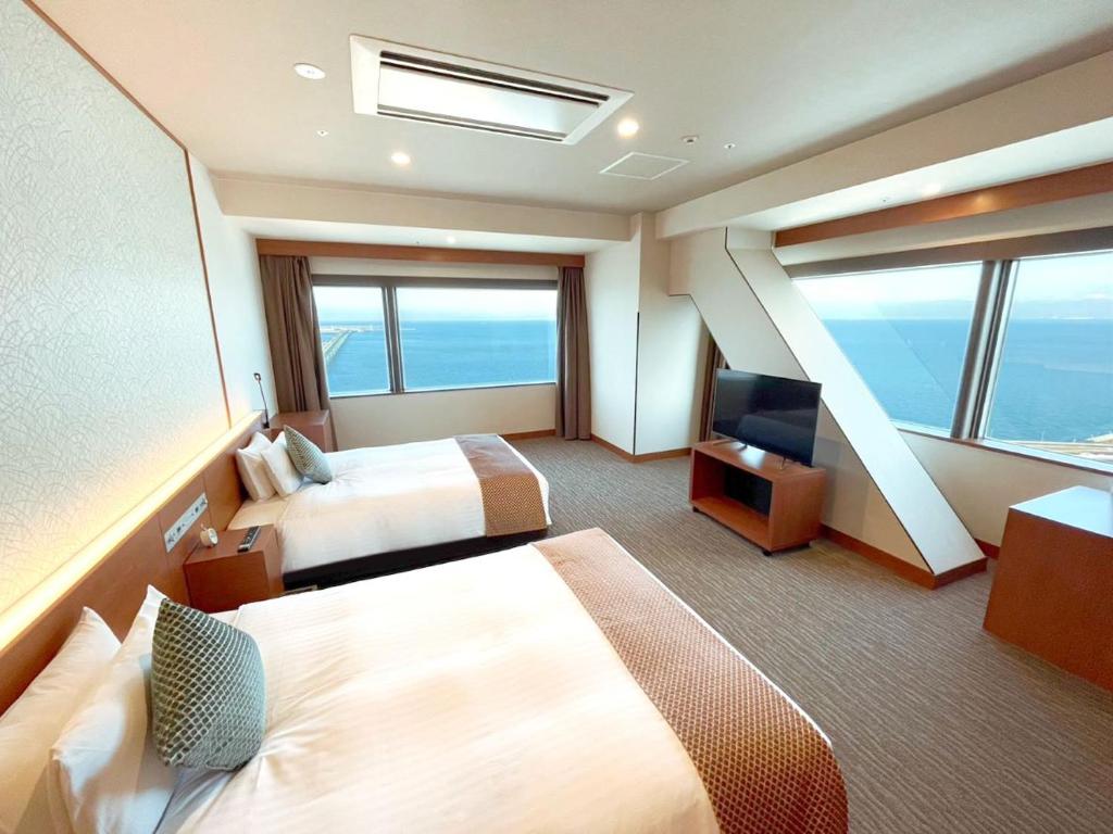 a hotel room with two beds and a television at Odysis Suites Osaka Airport Hotel in Izumi-Sano