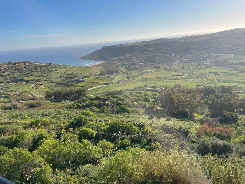 uma vista para um campo verde com o oceano ao fundo em Entire apartment with Ramla Bay view (Gozo, Malta) em Il-Pergla