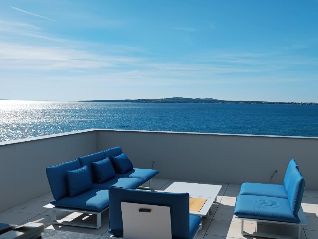 a balcony with blue chairs and a view of the ocean at Aparthotel Dalmacija in Privlaka