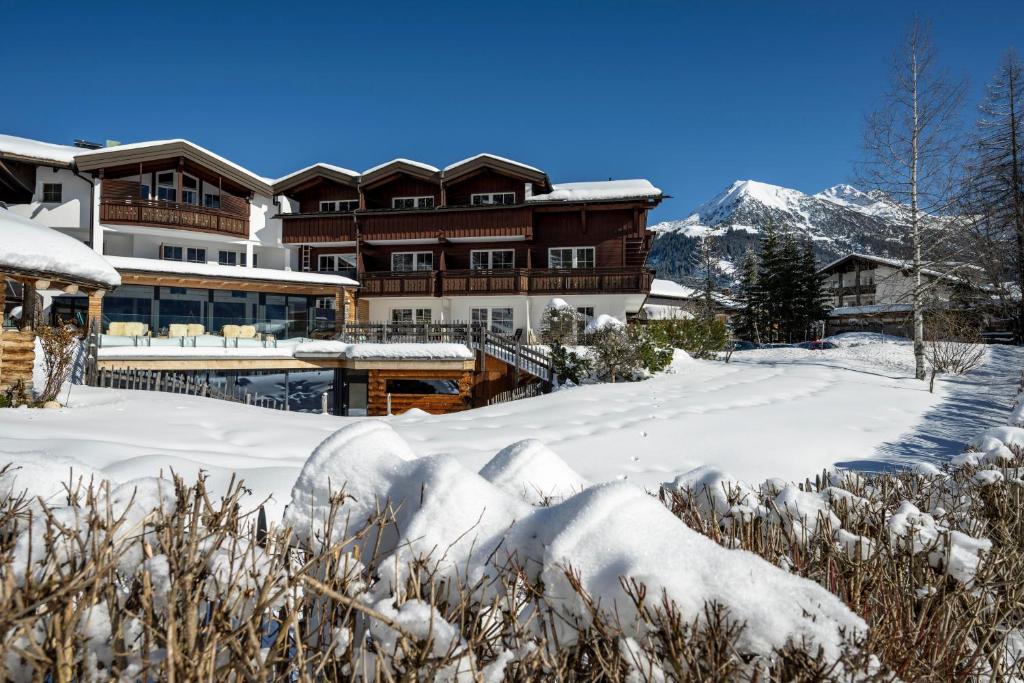 un lodge dans la neige avec des montagnes en arrière-plan dans l'établissement Naturhotel Lärchenhof, à Mittelberg