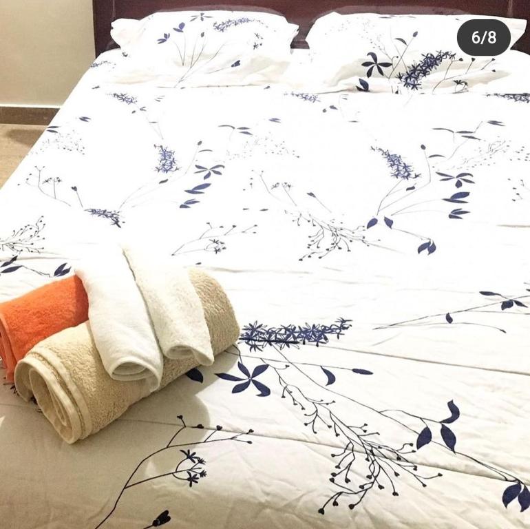 Somvārpet的住宿－Little bungalow Holiday Home, Coorg，一张带蓝色花卉的白色床单的床