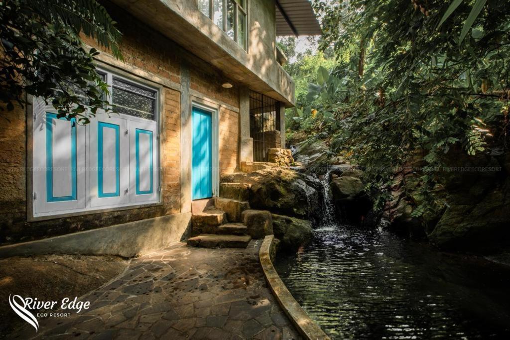 une maison avec une fontaine située à côté d'un bâtiment dans l'établissement River Edge Eco Resort, à Kitulgala