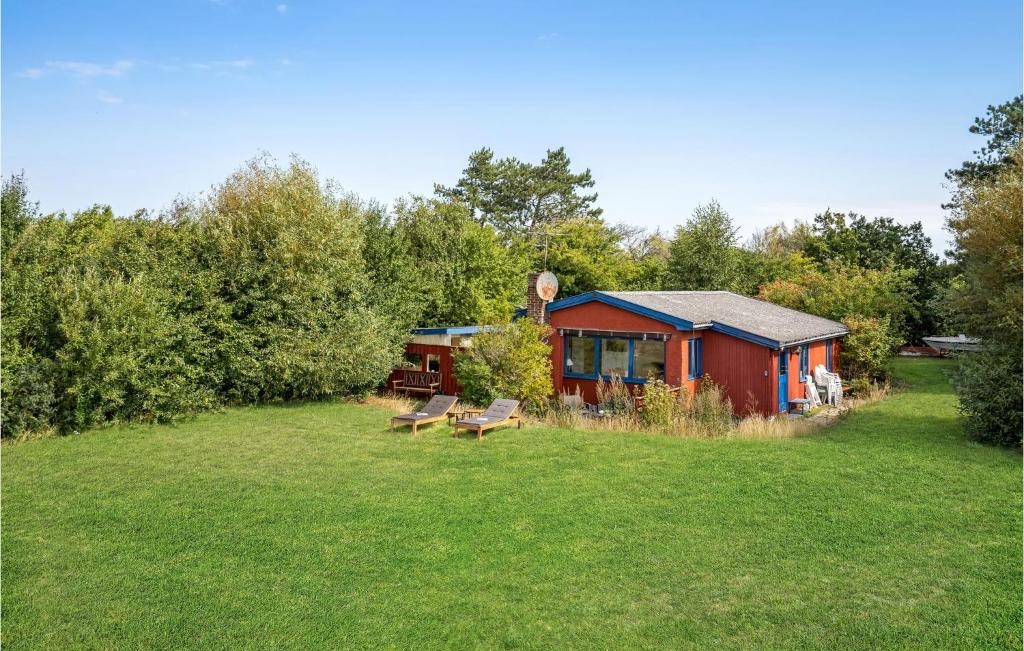 a red cabin in the middle of a grass field at Beautiful Home In Slagelse With House Sea View in Slagelse