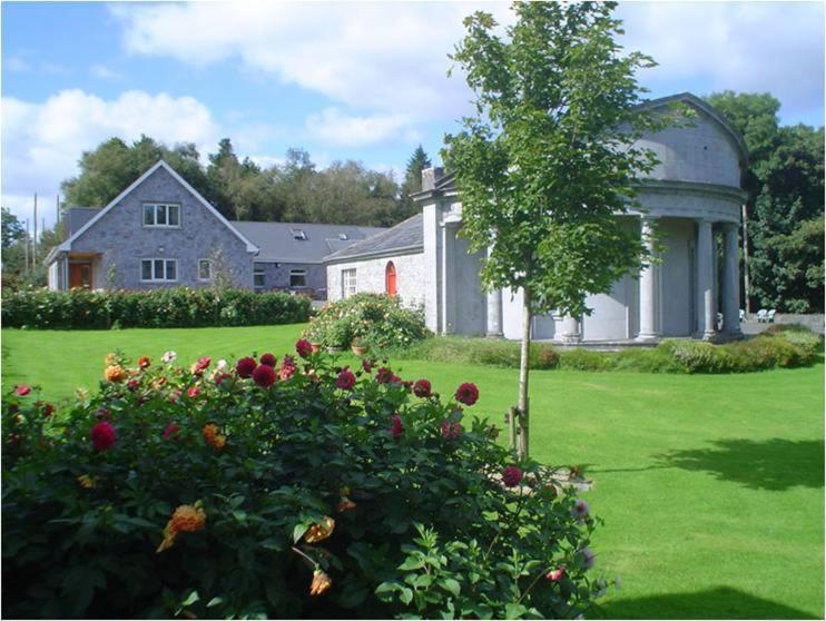 une grande maison blanche avec un arbre dans une cour dans l'établissement Forest Park House B&B, à Boyle