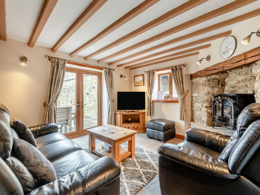 a living room with leather furniture and a stone fireplace at The Old Dairy in Clay Cross