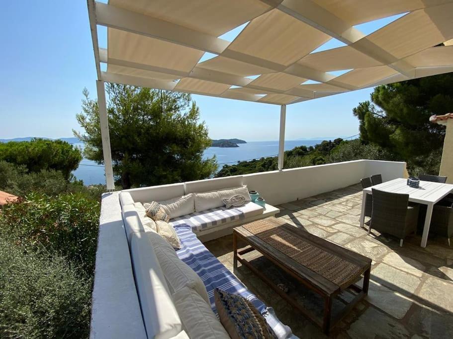a patio with a couch and a table and an umbrella at Villa Bounatsa with access to semi-private beach in Kanapitsa