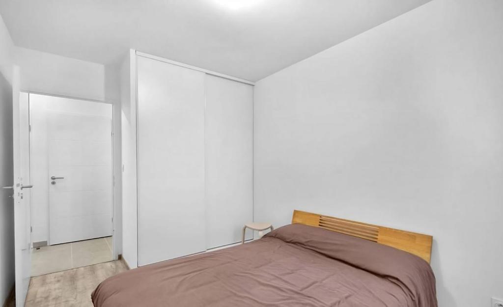 a bedroom with a bed and a white wall at Le Lamartine - T3 dans un parc in Frouzins