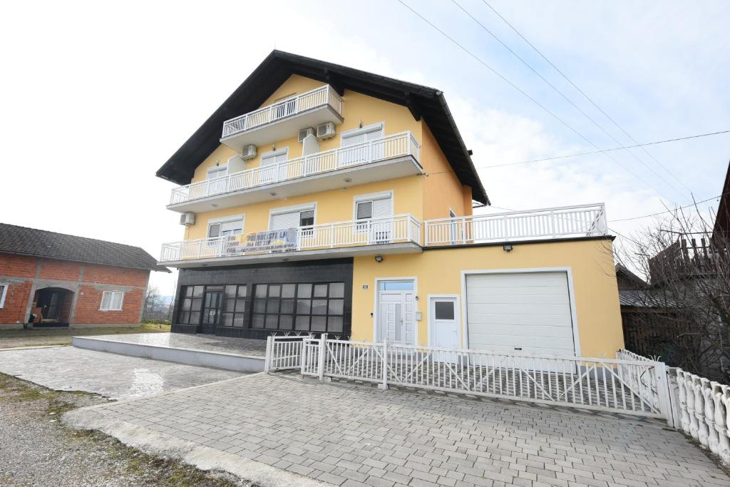 a yellow house with a white fence in front of it at LM Rooms in Banja Luka