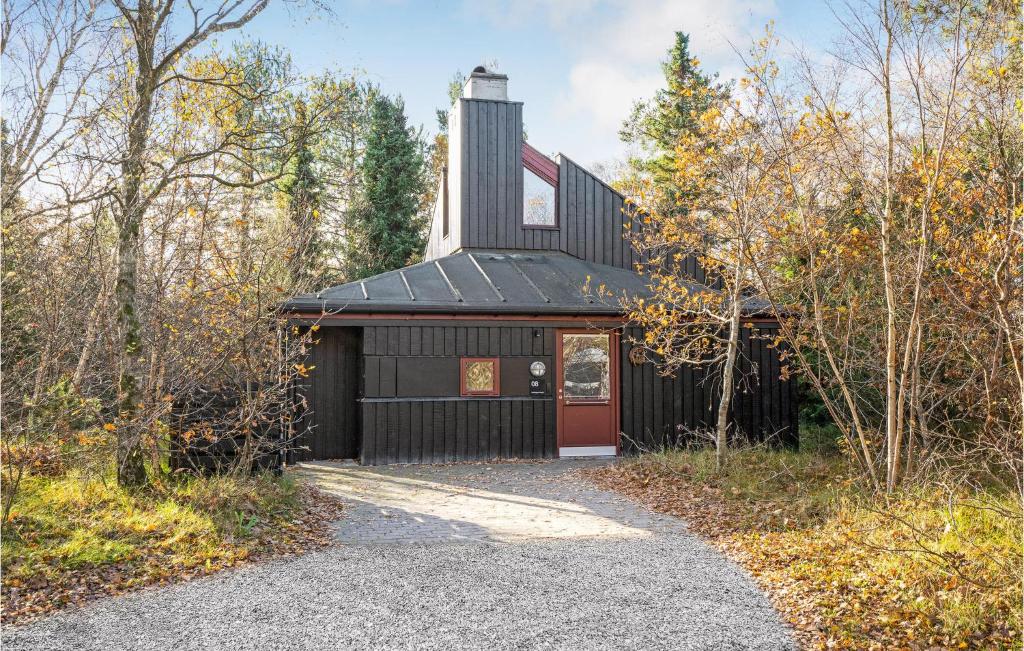 eine schwarze Scheune mit einer roten Tür und einer Kirche in der Unterkunft 2 Bedroom Gorgeous Home In Grenaa in Grenå