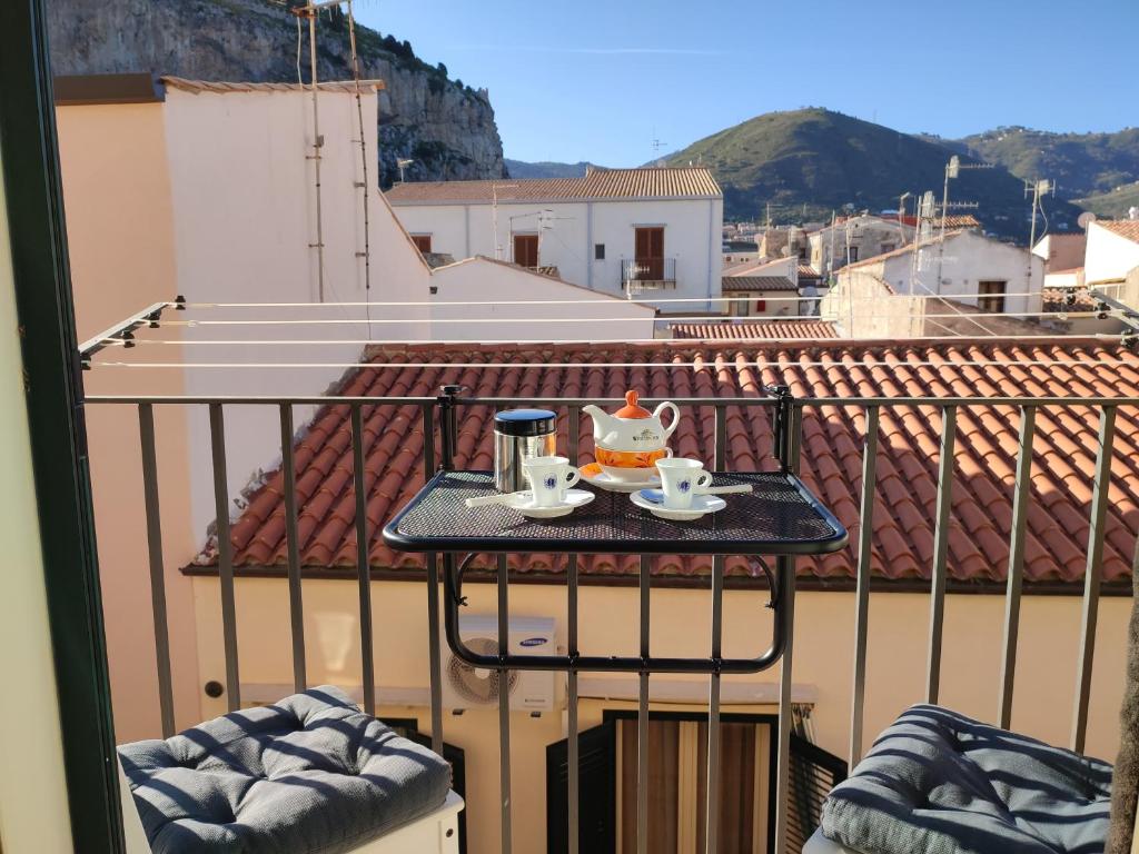 a table with a tea set on top of a balcony at MOLO 78 Case Vacanze in Cefalù