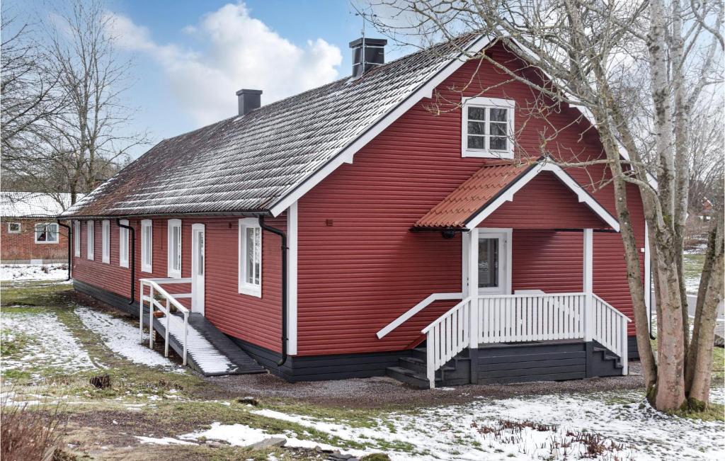 uma casa vermelha com um telhado de gambrel com neve em Nice Home In Orrefors With Jacuzzi em Orrefors