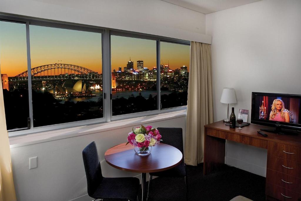 um quarto de hotel com uma secretária e uma mesa com flores em Macleay Hotel em Sydney