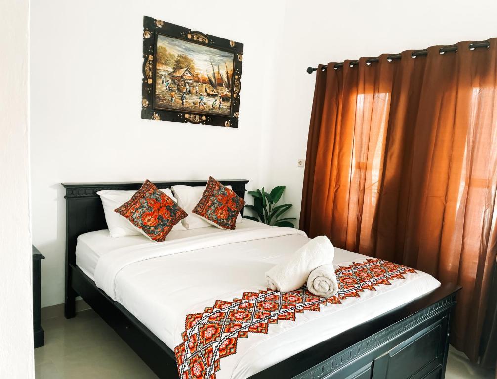 a bedroom with a bed with white sheets and orange curtains at Nusa Penida Homestay in Nusa Penida