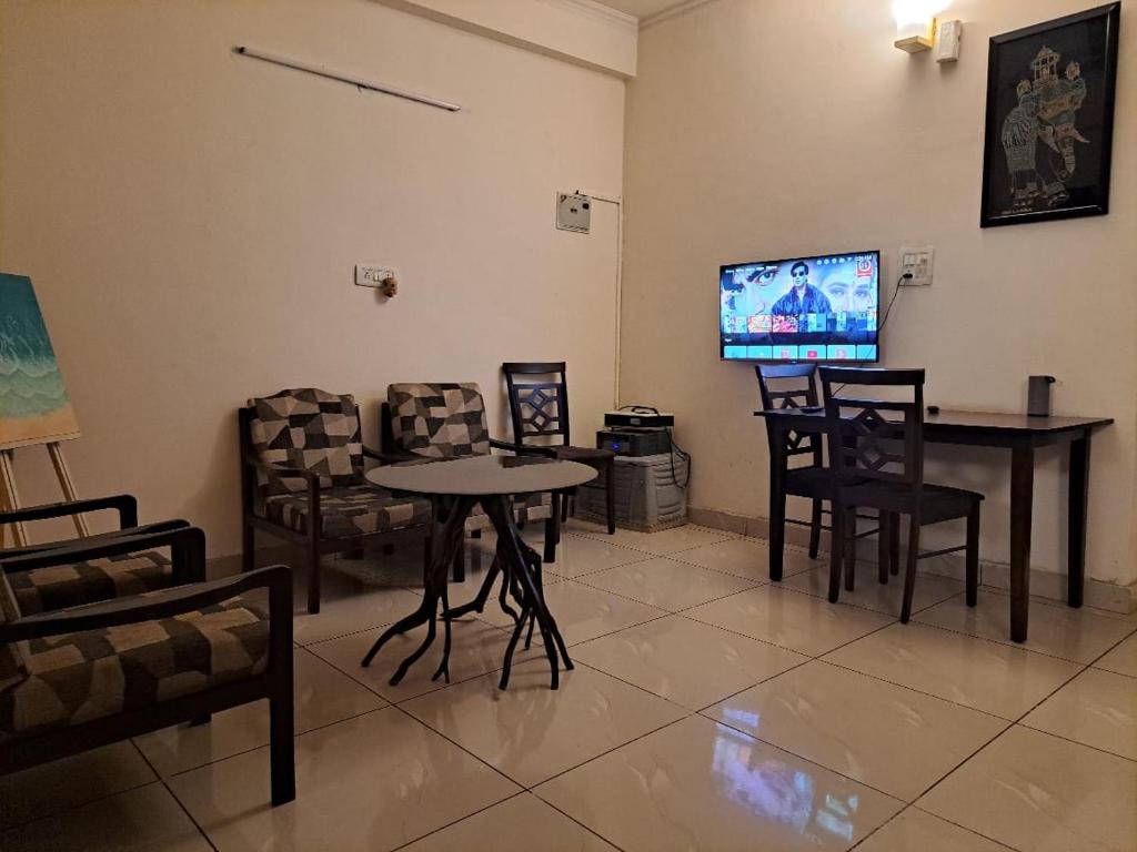 sala de estar con mesa, sillas y TV en Private room with Sky Garden in Green Bacchus by Walias en Gurgaon