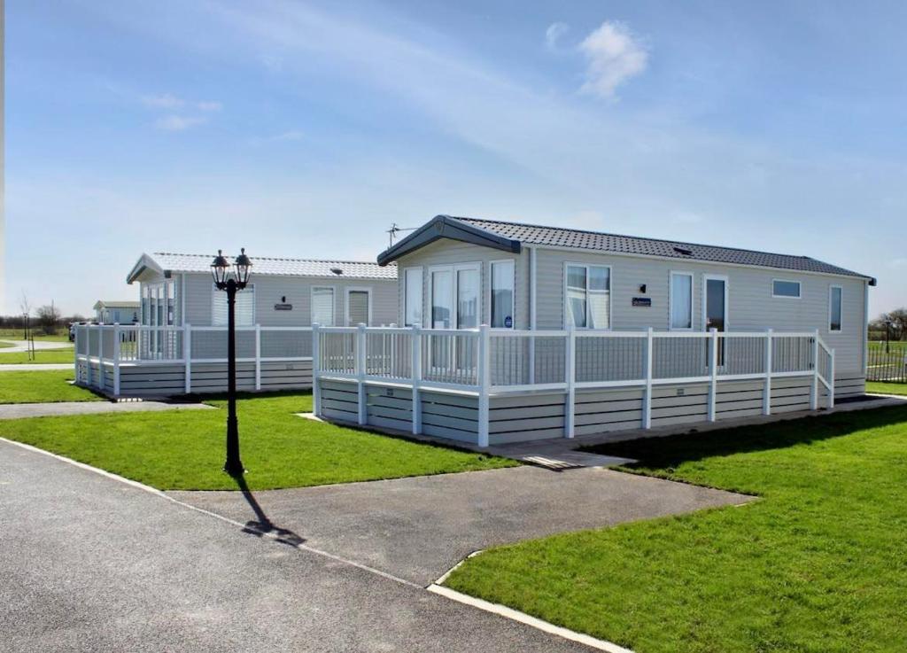 a large white house with a white fence at Honeysuckle Prestige Holiday Homes in Chapel Saint Leonards