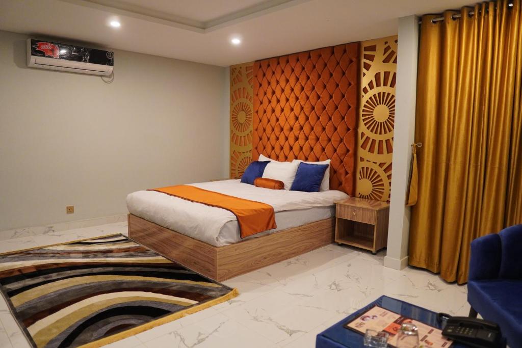 Schlafzimmer mit einem Bett mit orangefarbenen und blauen Kissen in der Unterkunft NuvaHotel in Islamabad