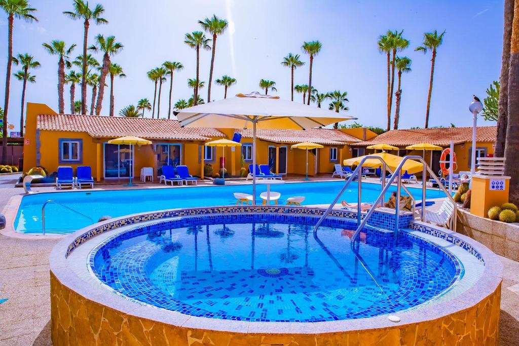 a pool at a resort with palm trees at Bungalows Los Almendros - Exclusive Vacation Club in Playa del Ingles