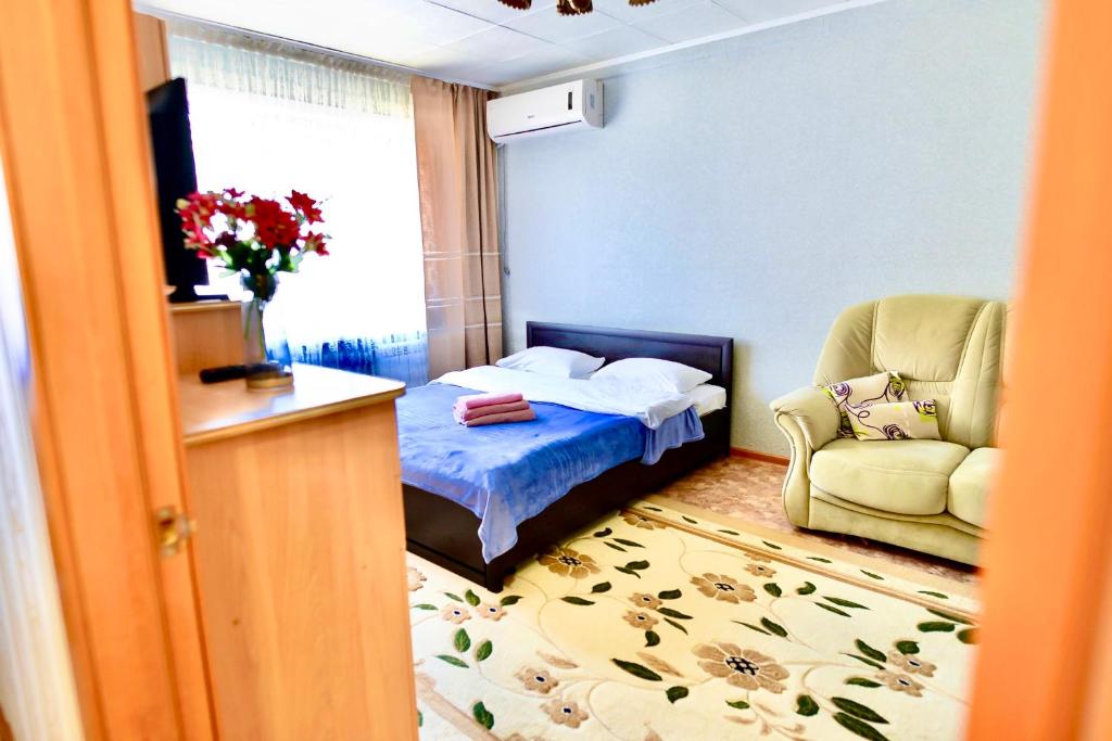 een slaapkamer met een bed, een stoel en een raam bij В центре Павлодара светлая квартира in Pavlodar