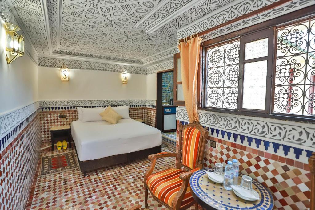 um quarto com uma cama, uma mesa e uma cadeira em Riad Farouzi Fes em Fez
