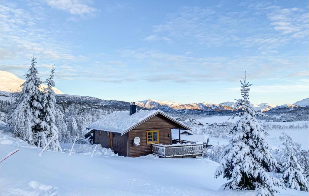 a small cabin in the snow with trees and mountains at Nice Home In Straumgjerde With Kitchen in Brunstad