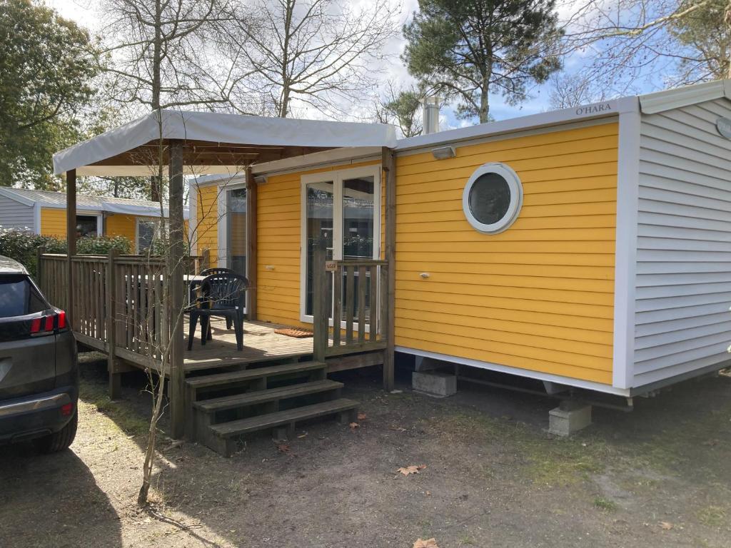 żółty domek z werandą i schodami w obiekcie Camping 5* - Biscarosse Lac - MobilHome 2 chambres - 4 personnes w mieście Biscarrosse