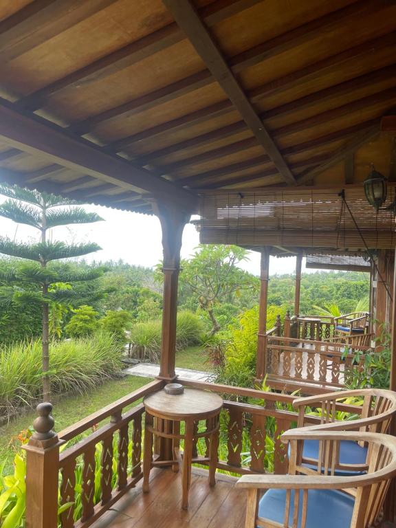 eine Veranda mit zwei Stühlen und einem Tisch darauf in der Unterkunft Kepaon Gari Inn in Nusa Penida