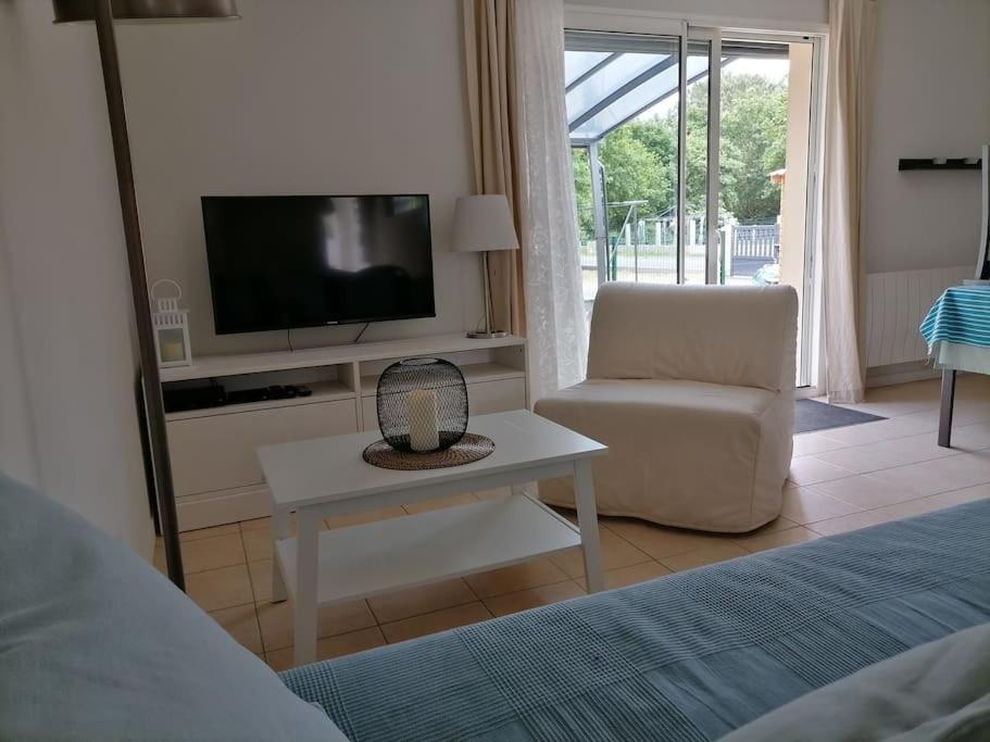 salon z telewizorem i krzesłem w obiekcie Maison chaleureuse proche plage du Gurp w mieście Grayan-et-lʼHôpital