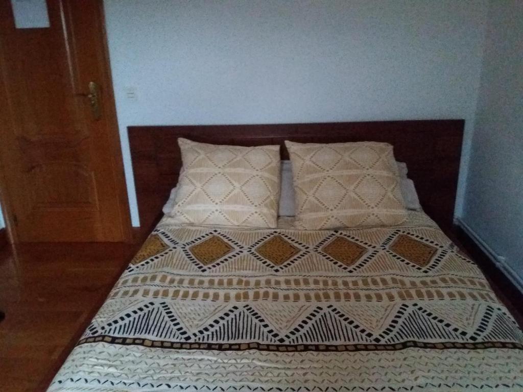 uma cama com cabeceira e almofadas de madeira em Vista Alegre em Zarautz