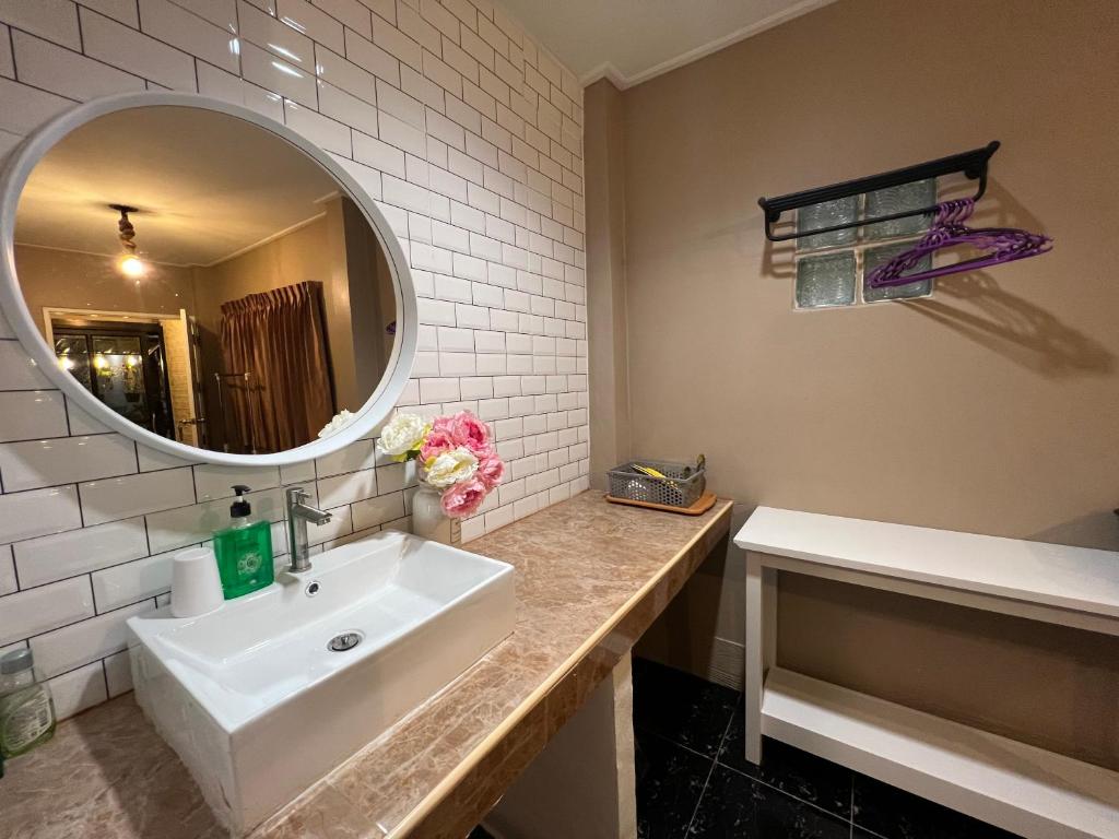 a bathroom with a white sink and a mirror at The One House in Nan