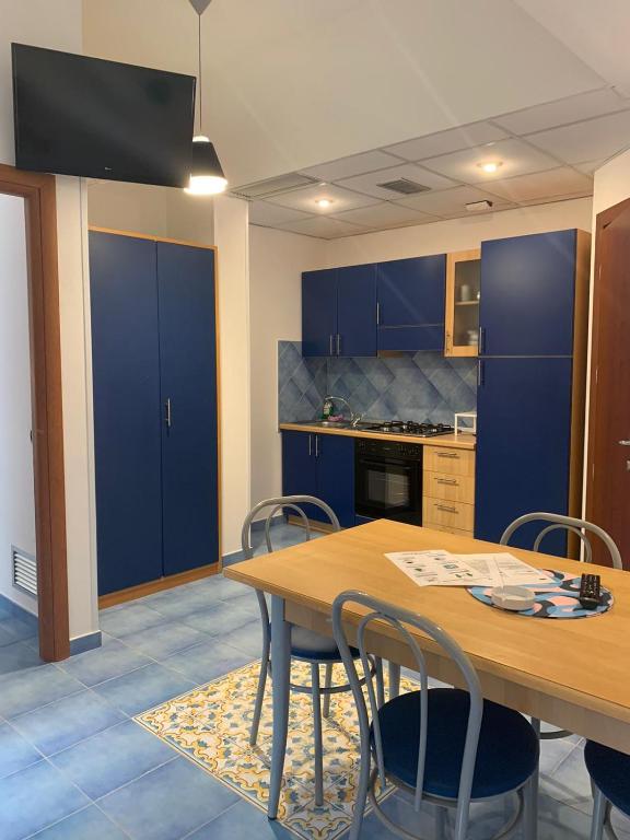 a kitchen with blue cabinets and a wooden table and chairs at Residence Panoramic in Maiori