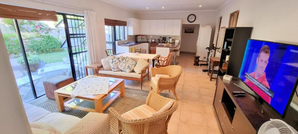 a living room with a couch and a table and a tv at Guinea Fowl poolside apartment in Cape Town