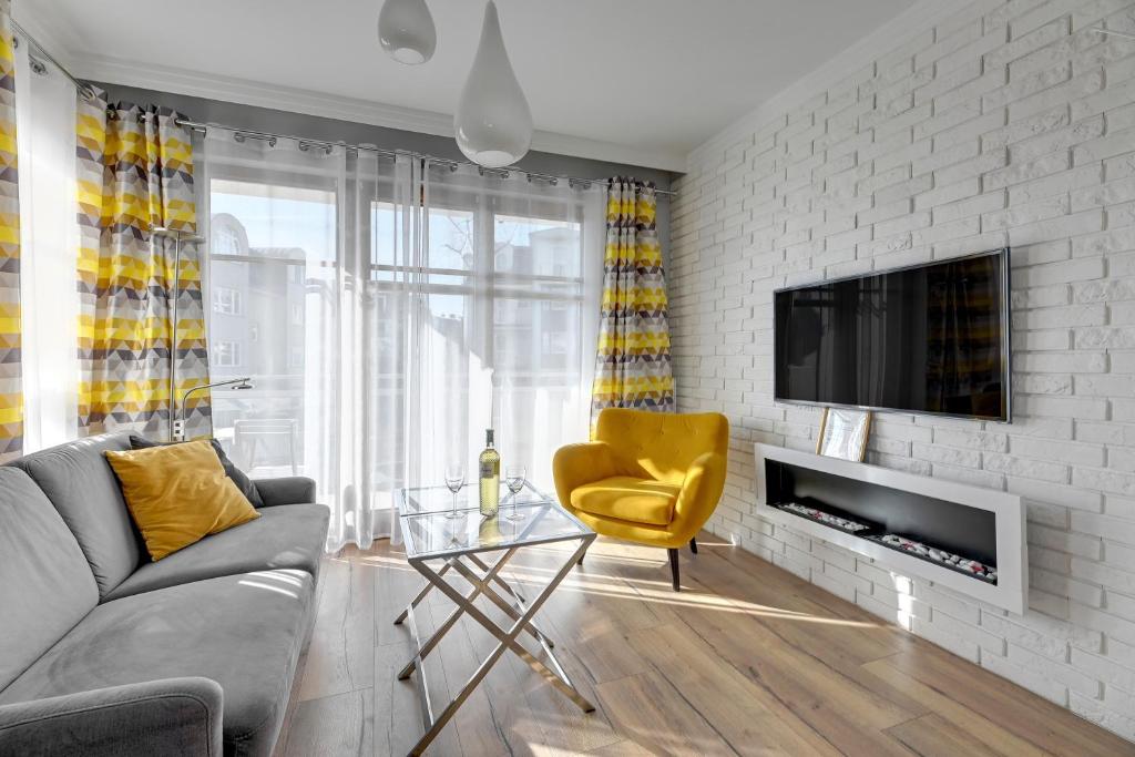 a living room with a couch and a yellow chair at Sopocka Bryza - Baltica Apartments in Sopot