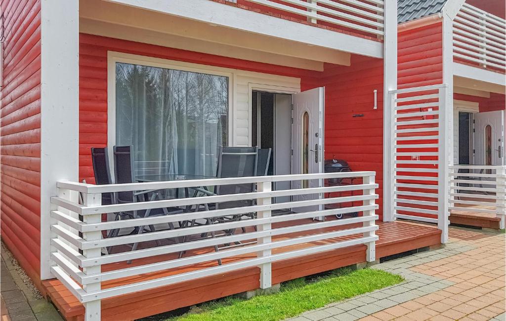 une maison rouge avec une clôture blanche sur une terrasse couverte dans l'établissement 2 Bedroom Stunning Home In Sianozety, à Sianożęty