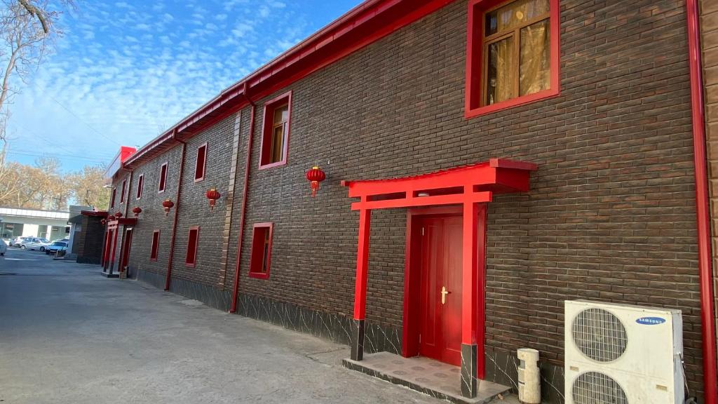 un edificio de ladrillo con una puerta roja en una calle en JINJU en Yakkasaray