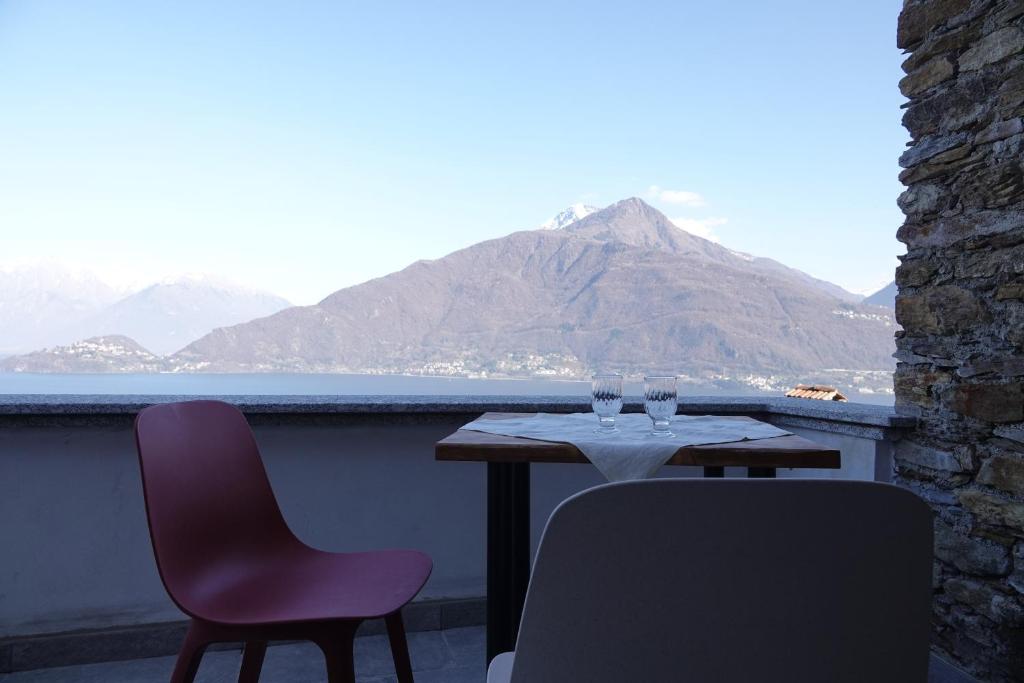 a table and chairs on a balcony with a view of a mountain at Casale Bella.Vista in Pianello Del Lario