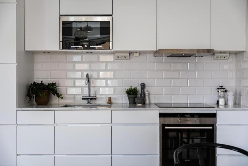 a kitchen with white cabinets and a sink at Beautiful and modern accommodation near Stockholm City in Stockholm