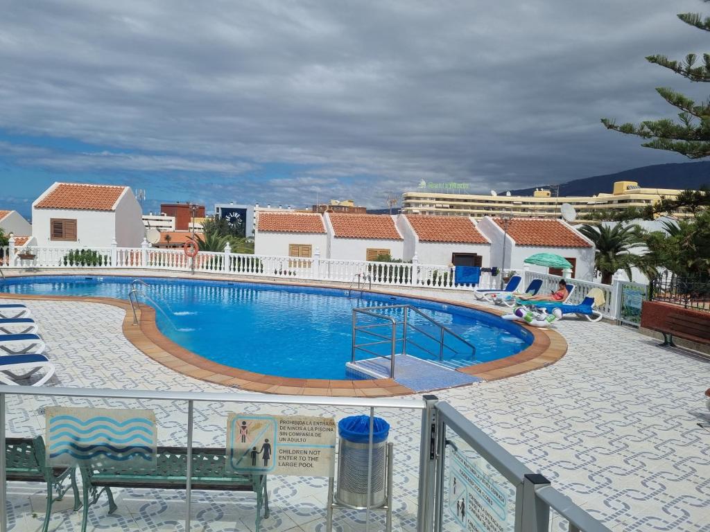 ein großer Pool in einem Resort mit Stühlen und Gebäuden in der Unterkunft Casa de Palmeras in Adeje