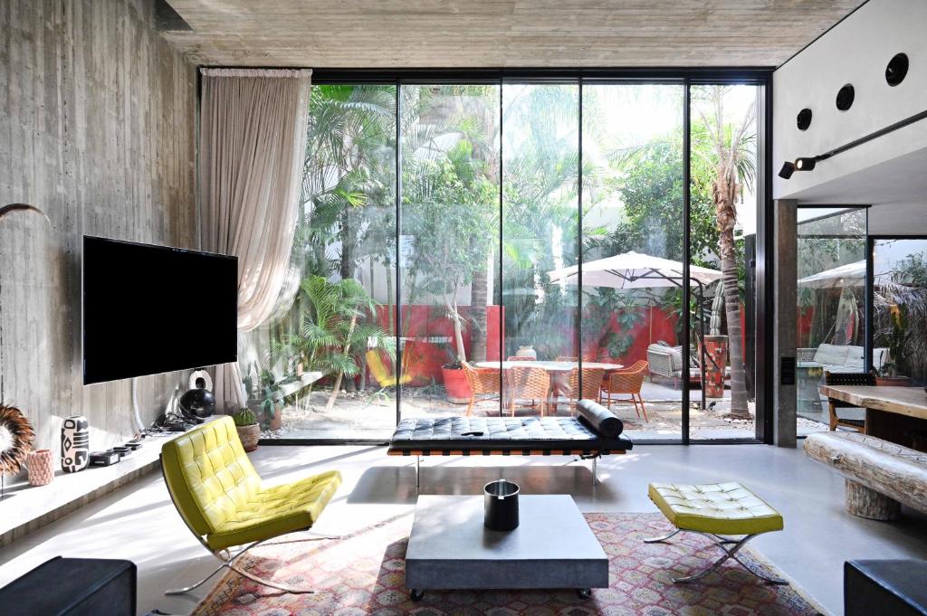 a living room with yellow chairs and a tv at The Eucalyptus Mansion by HolyGuest in Tel Aviv