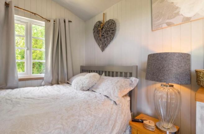 a bedroom with a white bed and a window at Nefoedd Romantic Shepherds Hut in Swansea