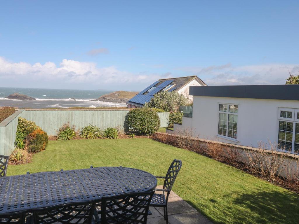 a patio with a table and chairs in a yard at Cormorant in Holywell Bay