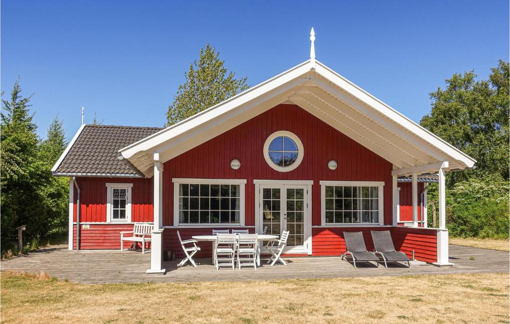 Gorgeous Home In Aakirkeby With Wifi في Vester Sømarken: بيت احمر امامه طاوله وكراسي