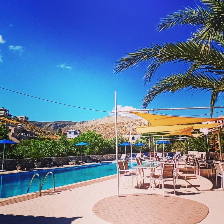a pool with chairs and umbrellas and a palm tree at Villa Maria in Kalymnos