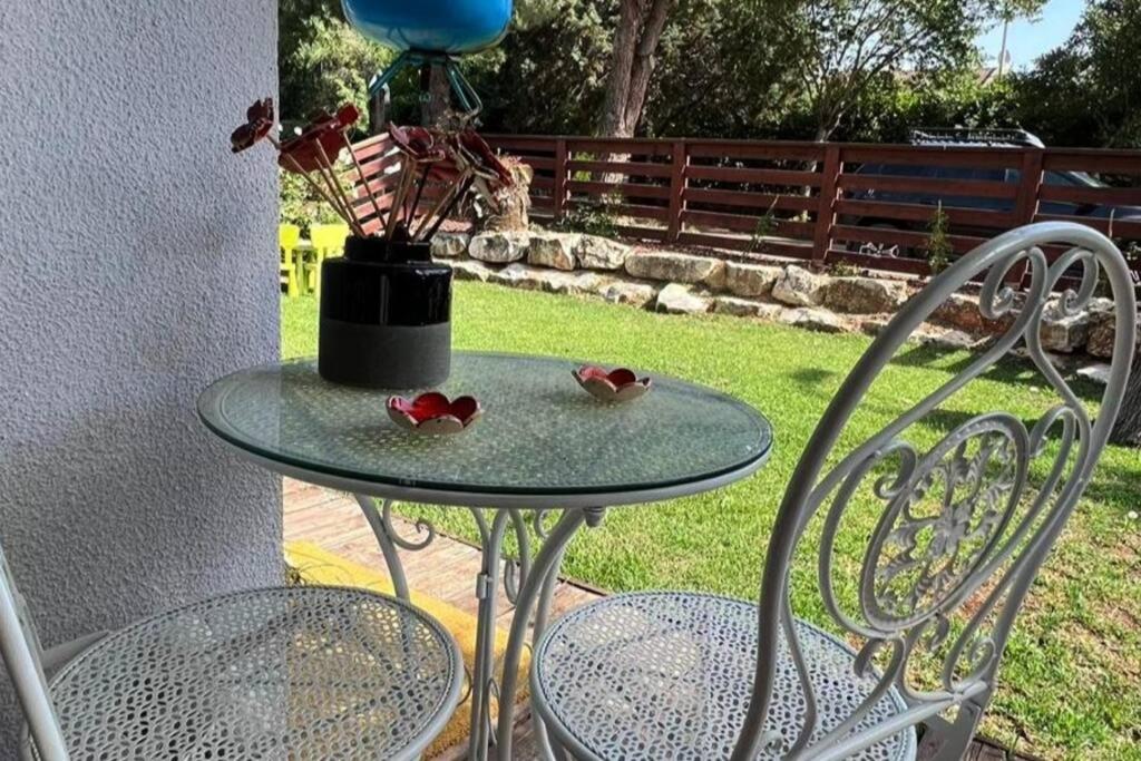 a glass table with two chairs and a vase on it at יחידת דיור נעימה, יפה ומוארת עם חצר קדמית גדולה in ‘Ilūṭ