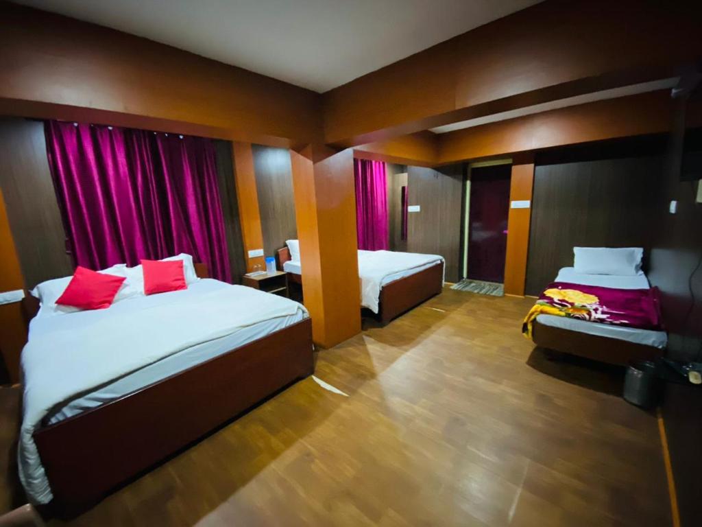 Habitación de hotel con 2 camas con almohadas rojas en Mananyaa Cottage en Ooty