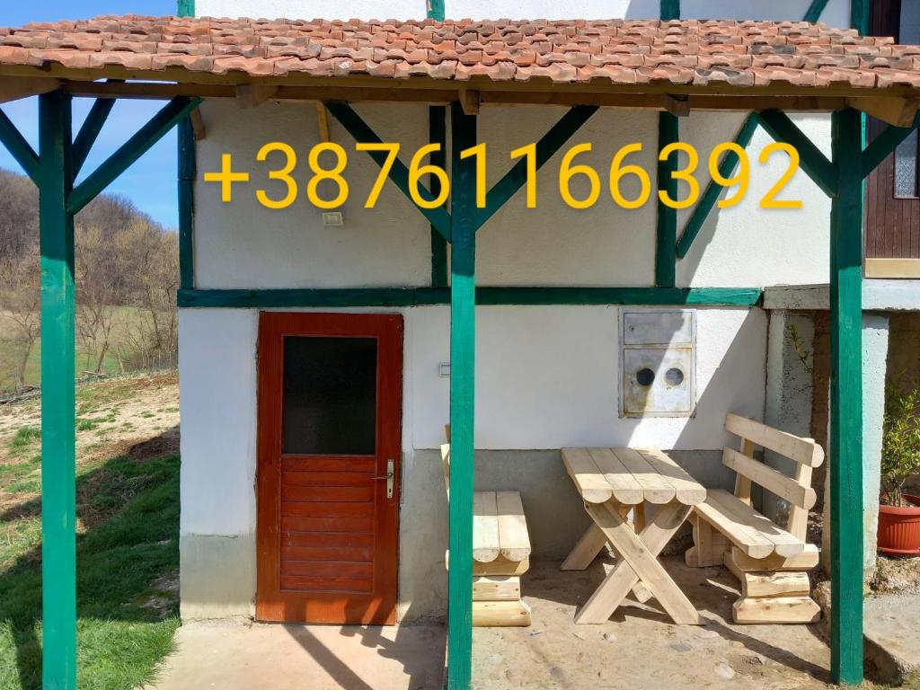 una pequeña casa con una puerta roja y un banco en Kuca za odmor-P-, en Visoko
