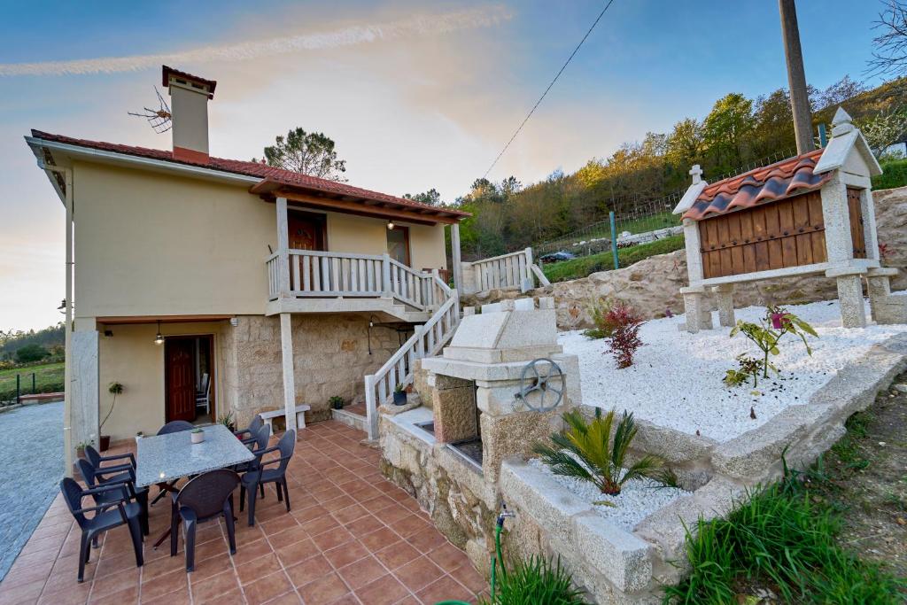 a house with a patio with a table and chairs at O Lar de Lola in Mondariz