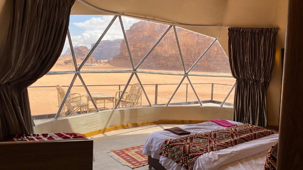 a bedroom with a large window with a view of a desert at Wadi Rum Khalid luxury camp in Wadi Rum