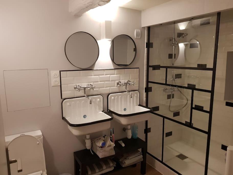 La salle de bains est pourvue de 2 lavabos, de miroirs et de toilettes. dans l'établissement Charmant gîte avec poêle à bois, à Pleslin-Trigavou