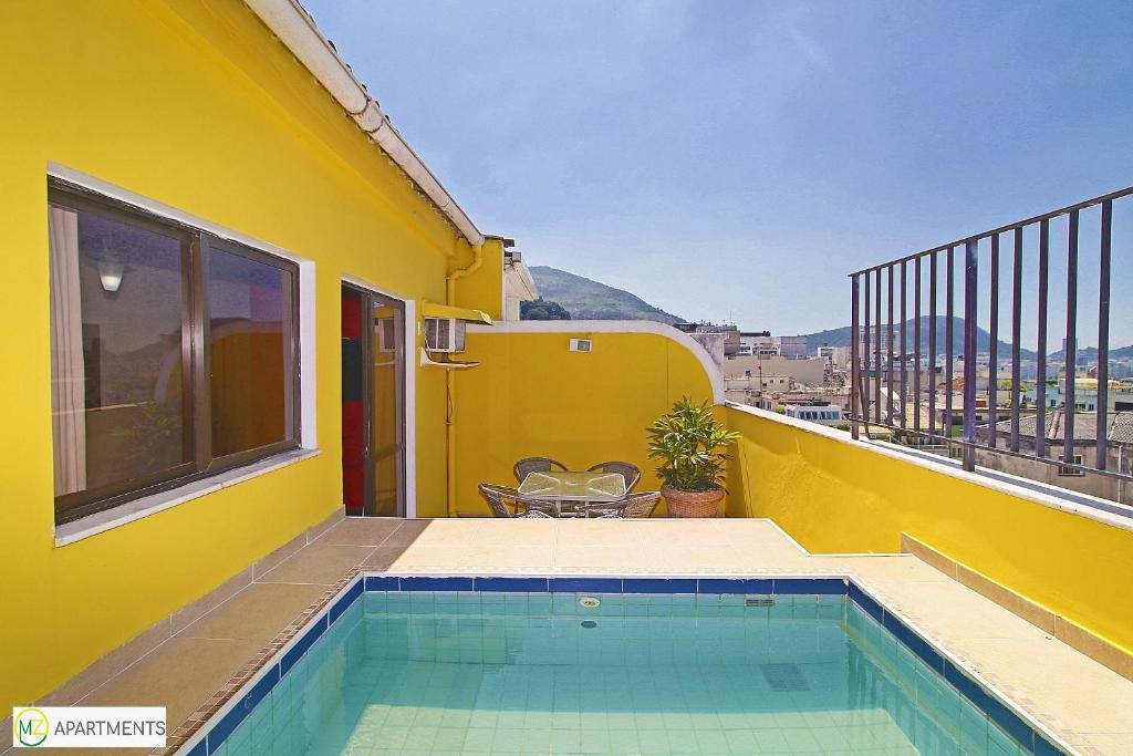 une maison jaune avec une piscine sur un balcon dans l'établissement Linda Cobertura duplex com varanda e piscina, à Rio de Janeiro